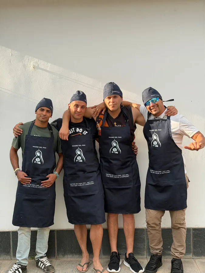 Cuatro integrantes del equipo, con delantal y gorro de Madre del Pan, posan contentos frente a una pared blanca